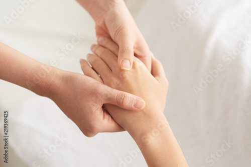 Beautician massaging hand of female spa salon client