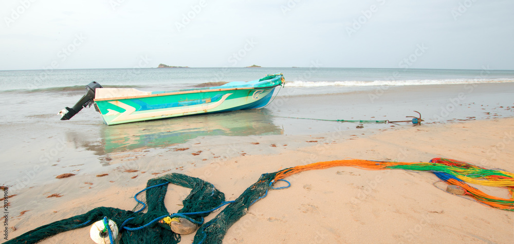 Small fishing boat next to curving fishing nets drying on Nilaveli
