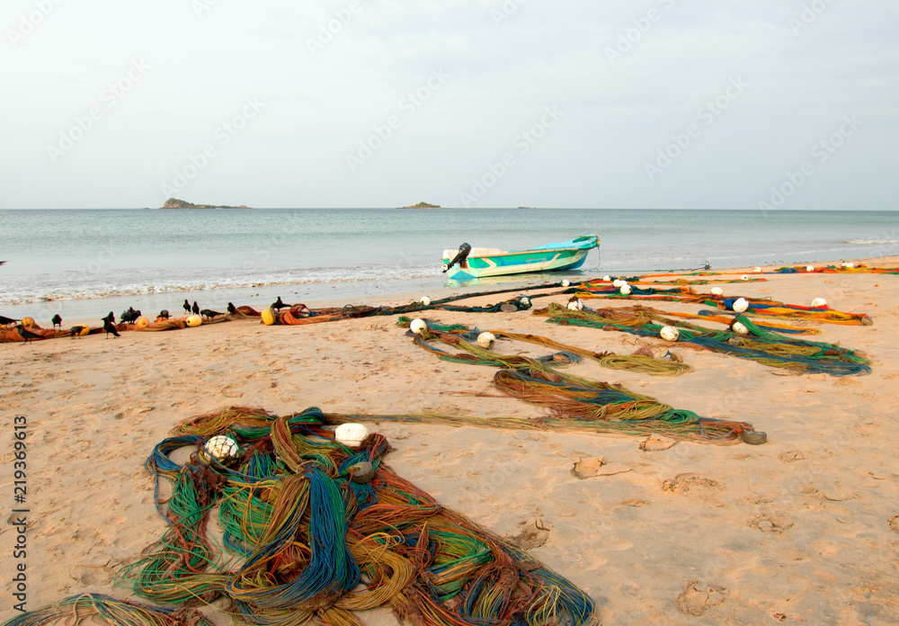 Small fishing boat next to curving fishing nets drying on Nilaveli beach in  Trincomalee Sri Lanka Asia Stock Photo