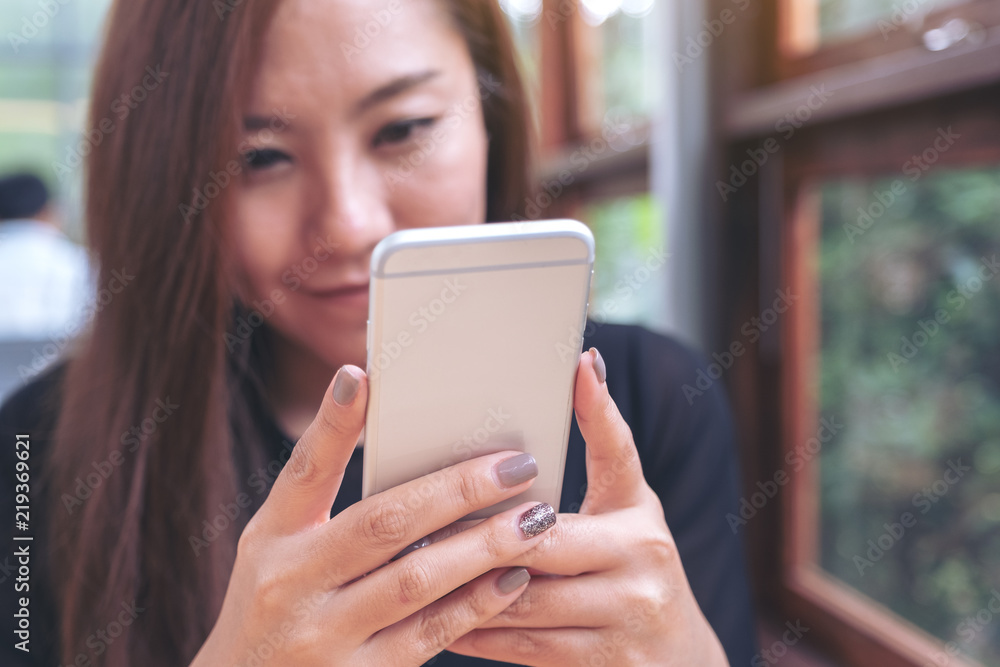 Closeup image of a beautiful Asian woman holding , using and looking at smart phone with feeling happy