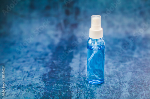 Spray bottle with blue liquid inside on blue grunge backdrop in selective focus