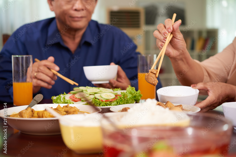 Hands of senior woman eating with chopsticks at family dinner Hands of senior woman eating with chopsticks at family dinner