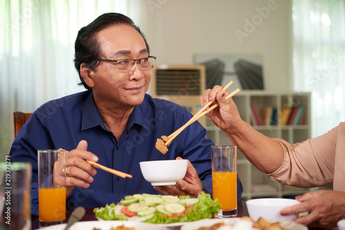 Senior Vietnamese man having tasty dinner at home with his wife