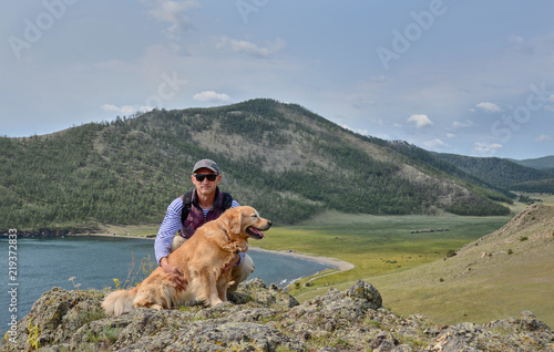 a man with a dog Retriever Golden sitting on the shore of lake B