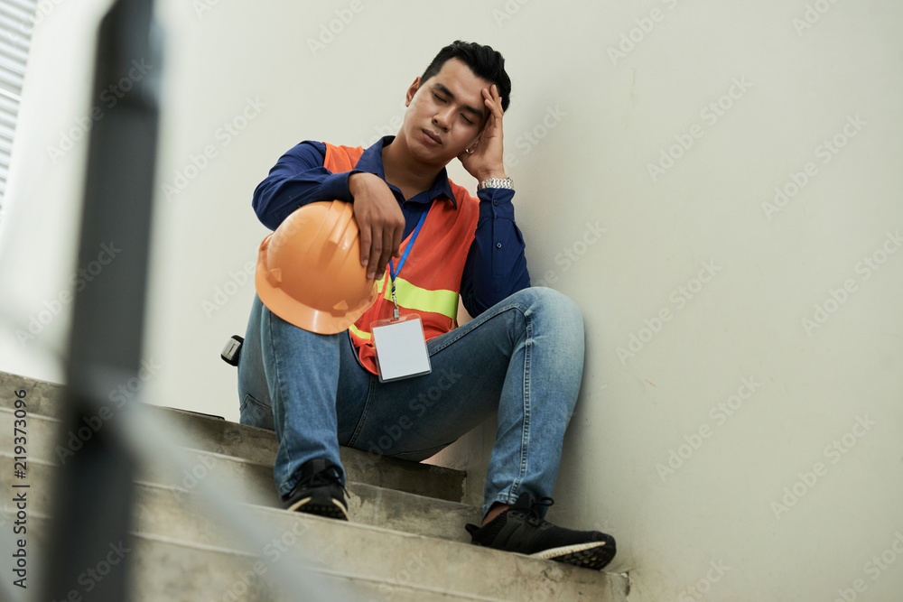 Stressed tired construction worker taking nap on stairs Stressed tired construction worker taking nap on stairs