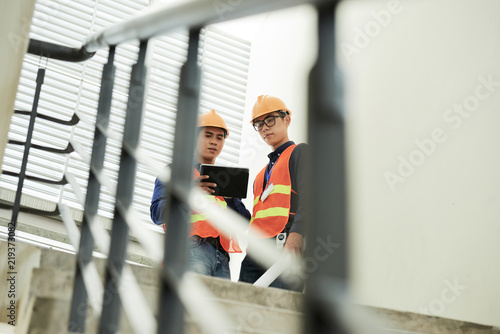 Construction site workers discussing data on tablet computer