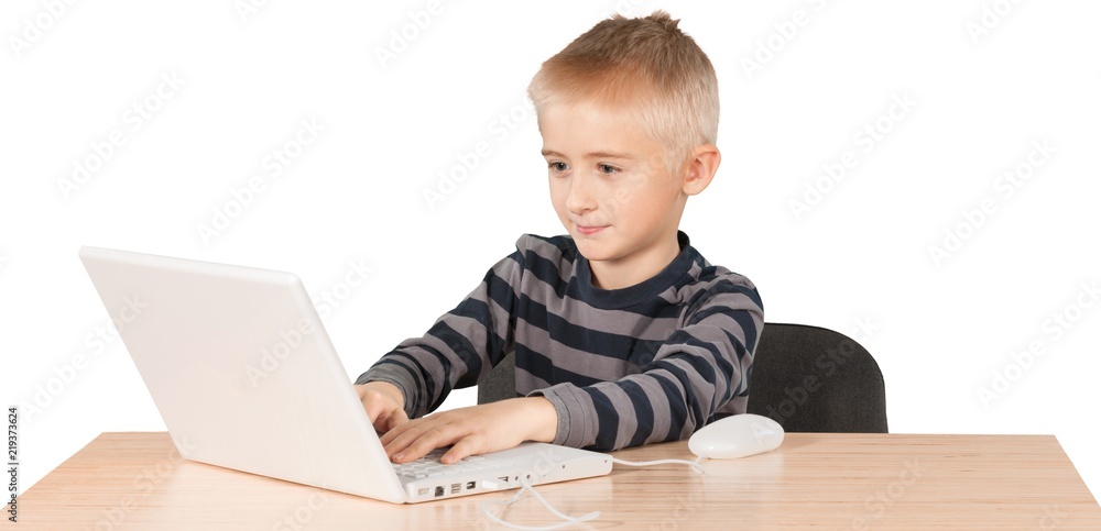 Young boy working on a laptop at a desk Young boy working on a laptop at a desk