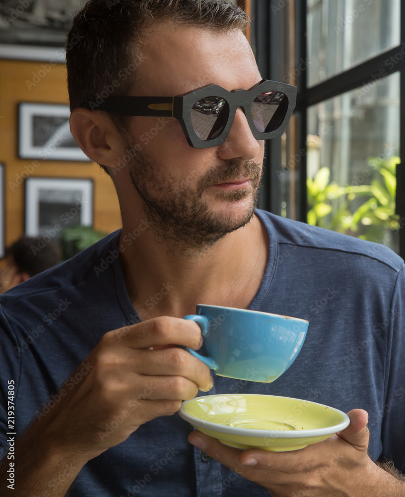 Young happy man drinks coffee in a restaurant or cafe Young happy man drinks coffee in a restaurant or cafe