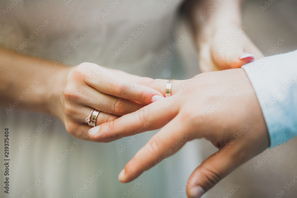 Woman wearing ring on man's hand on wedding ceremony closeup Stock
