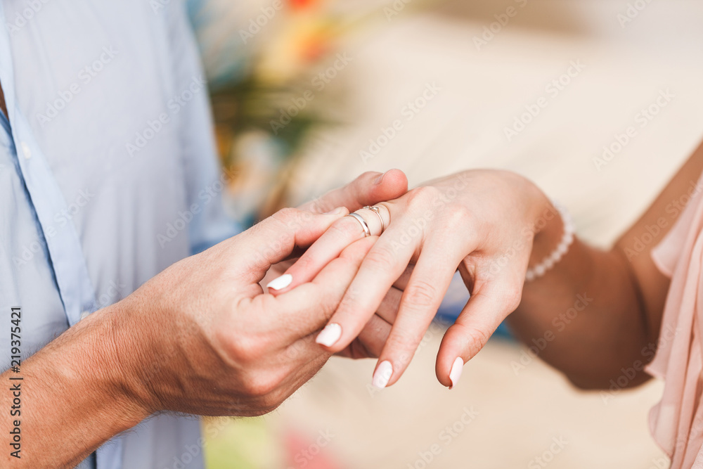 Groom wearing ring on bride's hand on wedding ceremony close-up Groom wearing ring on bride's hand on wedding ceremony close-up