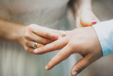 Woman wearing ring on man's hand on wedding ceremony close-up