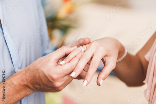 Groom wearing ring on bride's hand on wedding ceremony close-up © Oleg Breslavtsev