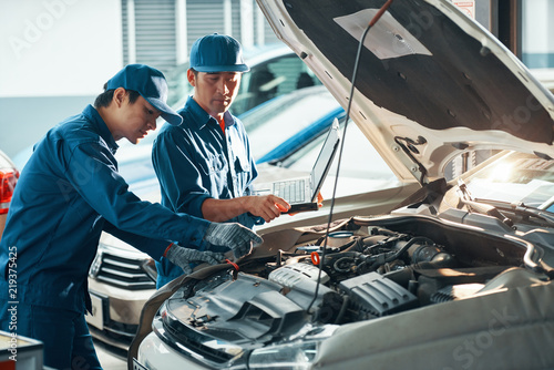 Mechanics using laptop when checking car in garage