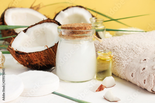 Fresh homemade coconut milk in glass jar, oil and nut for skin treatment, hair care, bathroom towel. Home spa with holistic coco nut products, healing lotion recipe. Safe, natural, aromatic.