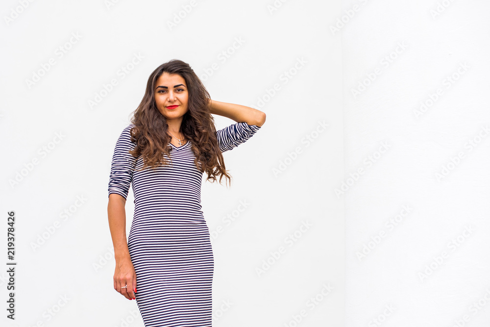Beautiful hispanic young woman in black and white striped dress at city. Autumn or spring fashionable trend Beautiful hispanic young woman in black and white striped dress at city. Autumn or spring fashionable trend