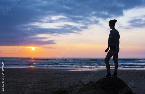 Girl on the beach at sunset with sun over the sea, city of San Sebastian