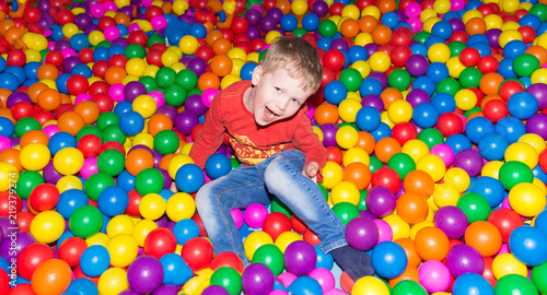 little boy having fun in a pool of colorful balls in the entertainment center © zayatssv