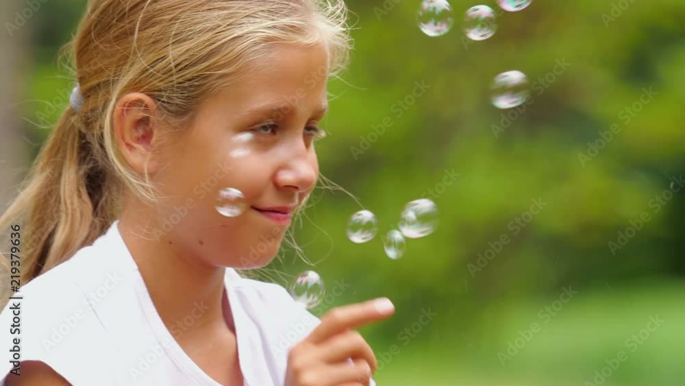 Nine-year-old girl playing with soap bubbles outdoor. Slow motion. Nine-year-old girl playing with soap bubbles outdoor. Slow motion.