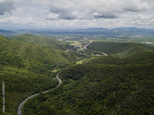 Aerial view of countryside road passing through the lush greenery and foliage tropical rain forest mountain landscape in the Northern Thailand