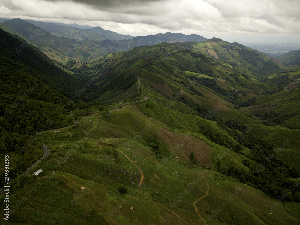 Aerial view of countryside road passing through the lush greenery and foliage tropical rain forest mountain landscape in the Northern Thailand Aerial view of countryside road passing through the lush greenery and foliage tropical rain forest mountain landscape in the Northern Thailand