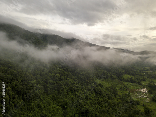 Aerial view of a village in the lush green rain cloud cover tropical rain forest mountain during the rainy season on the Doi Phuka Mountain reserved national park the northern Thailand © Kittiphat