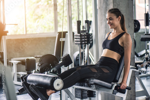 Cinematic tone of young attractive fitness woman exercise with machine in gym. Individual sport to fit muscles of body for healthy life concept. 
