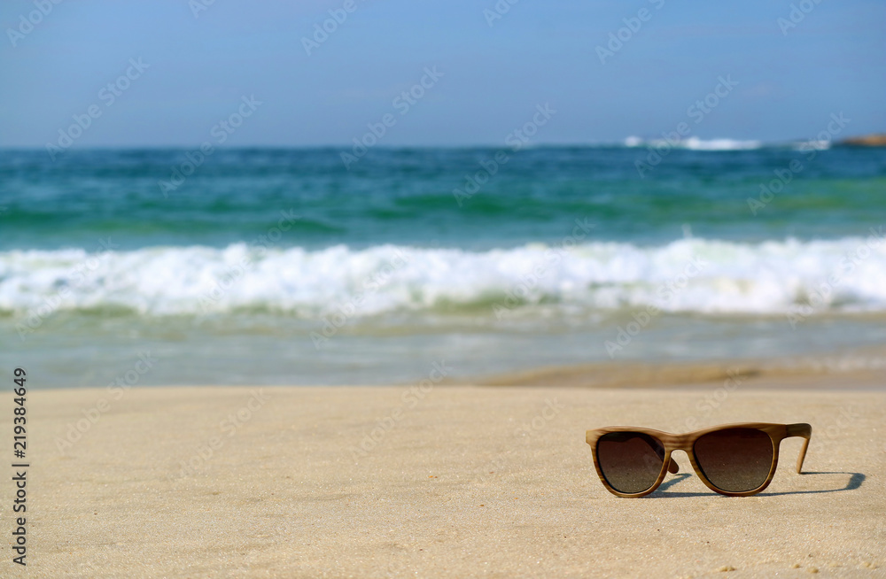 Sunglasses on the sandy beach with blurred Atlantic ocean in background, Rio de Janeiro, Brazil, South America 