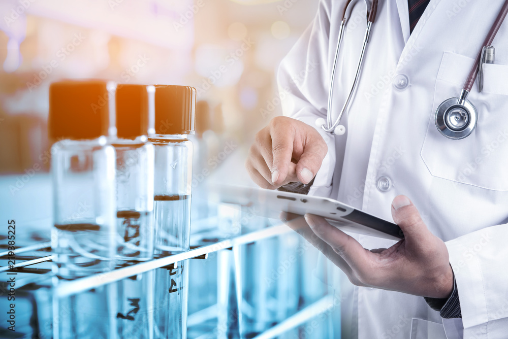 Doctor using tablet with lab glassware background Doctor using tablet with lab glassware background