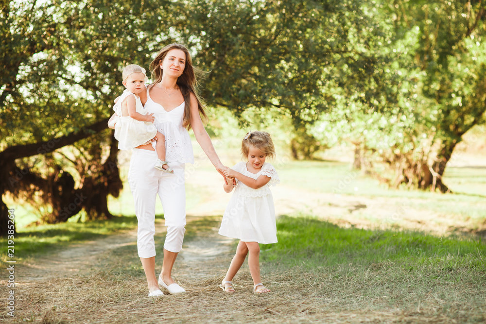 Mom with two little daughters are walking among the beautiful green forest. Mom with two little daughters are walking among the beautiful green forest.