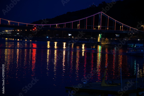 Blinking lights on night bridge, sparkle in water reflection