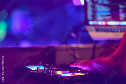 Dj mixes the track in the nightclub at party. DJ hands in motion