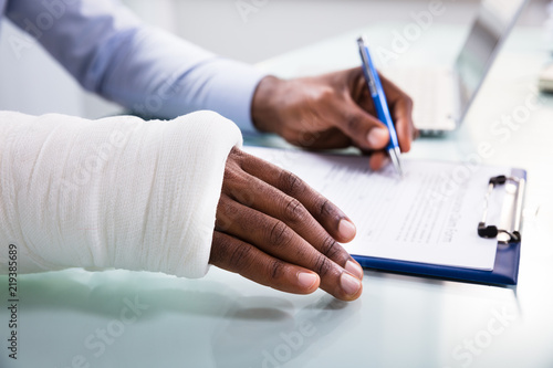 Injured Man Filling Insurance Claim Form photo