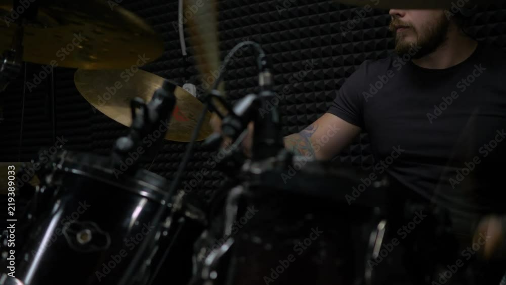 young man with tattoos playing a drum set in a dark room young man with tattoos playing a drum set in a dark room
