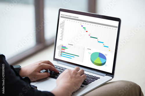 Man working with excel project dashboard on laptop / computer at office