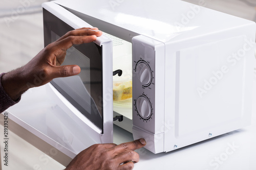 Man's Hand Heating Food In Microwave Oven