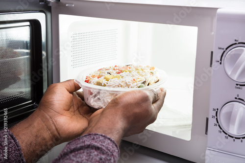 Man's Hand Heating Food In Microwave Oven