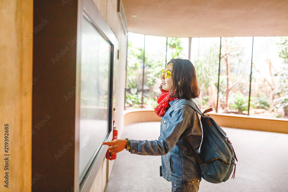 Fototapeta premium Woman use interactive modern touch screen monitor in zoological garden museum or just a zoo.