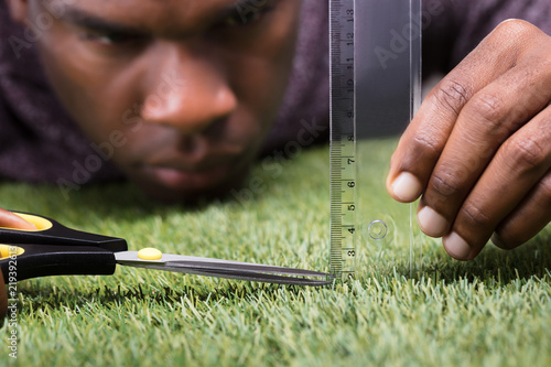 Man Cutting The Measured Grass With Scissor photo