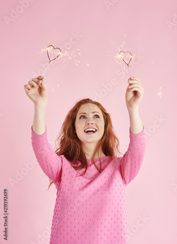 Woman holding heart shaped sparkler and looking up at studio