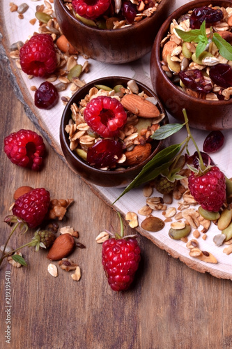 Granola decorated with raspberries in wooden bowls on the table