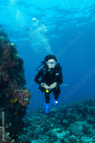 woman diver underwater over a colorful tropical reef with sea fan, coral and sponge in Rajat Ampat, Indonesia