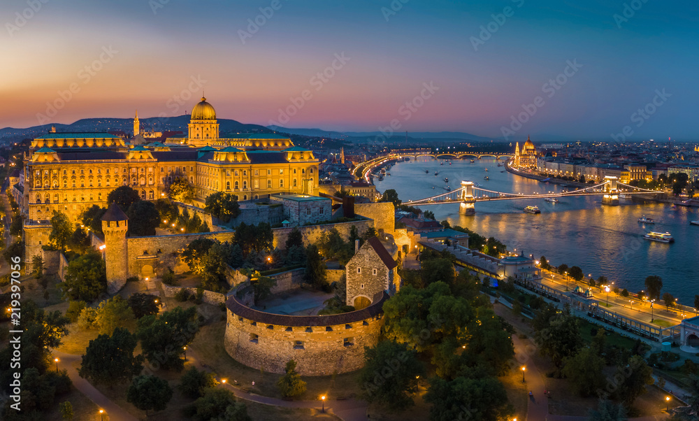 Naklejka premium Budapest Hungary - Aerial panoramic skyline view of Budapest at blue hour with Buda Castle Royal Palace, Szechenyi Chain Bridge, Parliament and sightseeing boats on River Danube