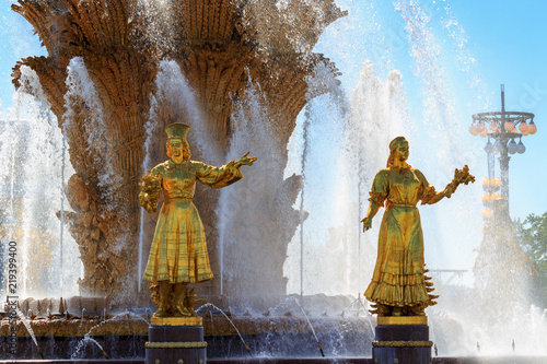 Gilded bronze girls symbolizing Republics of USSR against golden sheaf of wheat with technical hemp and sunflowers in fountain Friendship of peoples on VDNH in Moscow