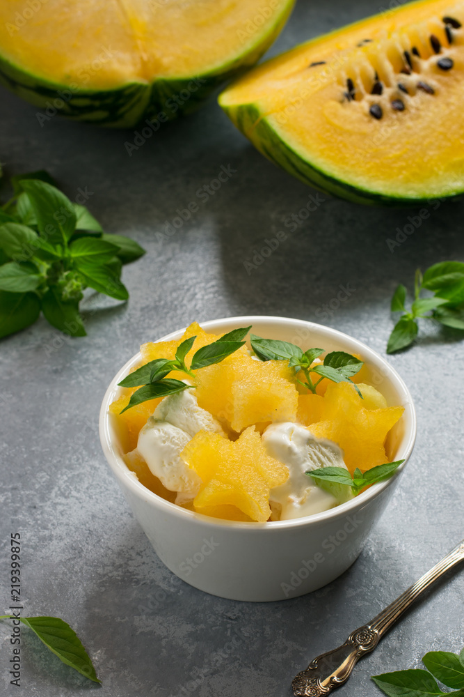 Stars of a yellow watermelon and ice cream for dessert, green leaves and a cut watermelon in the background Stars of a yellow watermelon and ice cream for dessert, green leaves and a cut watermelon in the background