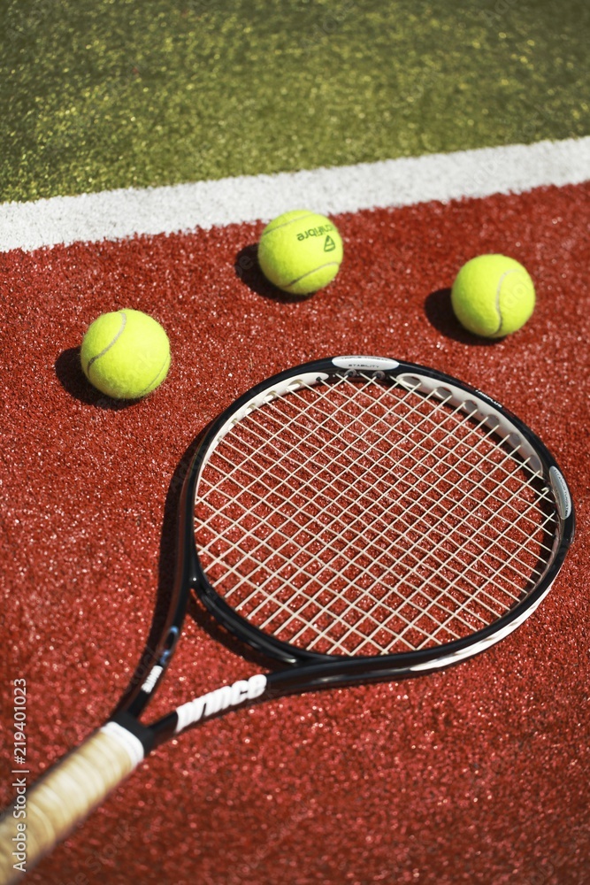 Tennis racket and tennis balls on a tennis court