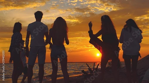 Group of people dancing at the beach near the bonfire. Slow motion.