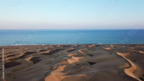 Horizon landscape of beautiful desert with sand dunes, the ocean on the background and blue sky in sunset light. Wonderful peaceful nature landscape, aerial. Gran Canaria photo