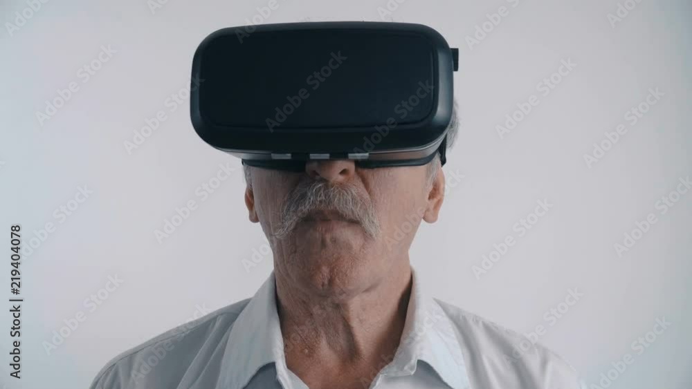 Senior man using his VR headset for watching the 360 video at white background Senior man using his VR headset for watching the 360 video at white background