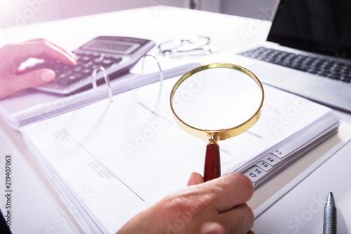 Businessperson Analyzing Bill With Magnifying Glass