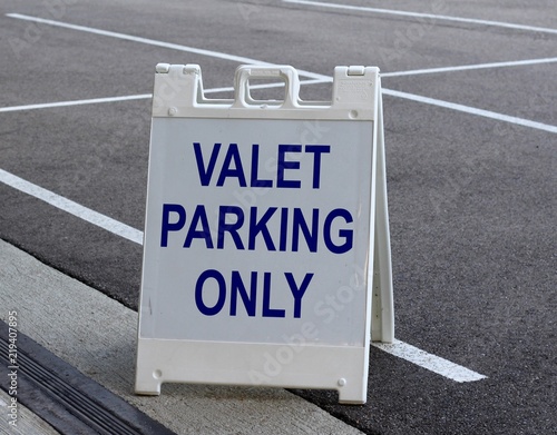 Картината върху платно A white and blue valet parking sign in the parking lot.